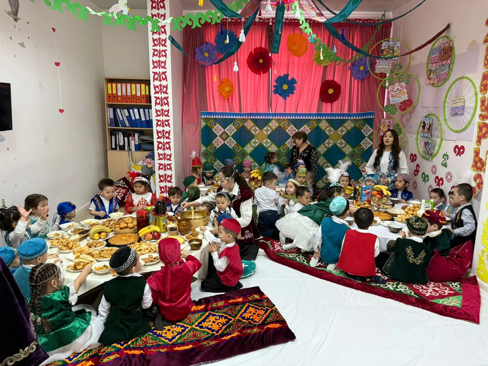 Ұлттық киімдегі балалар Наурыз дастарханының айналасында